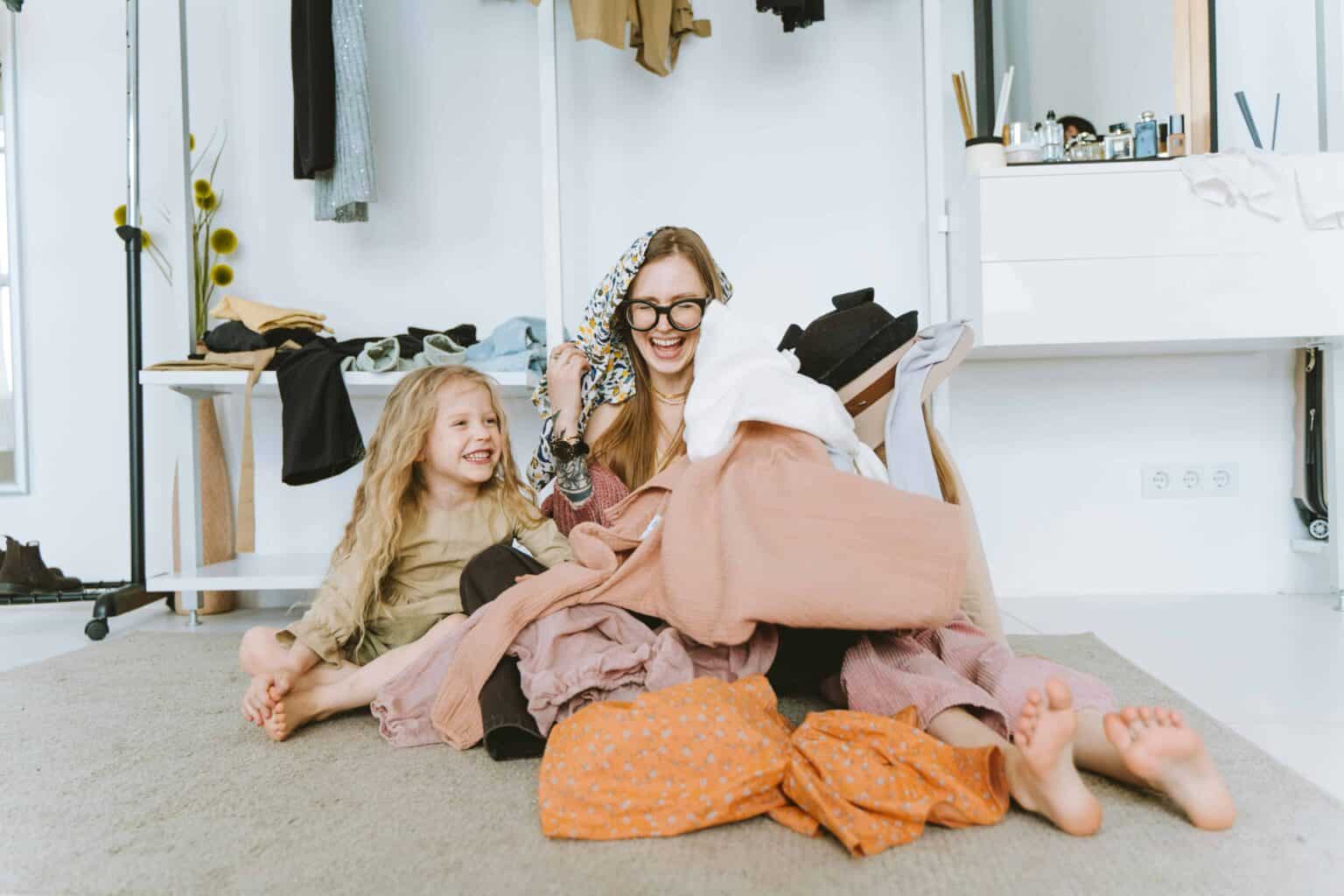 A mother and daughter playing in a pile of laundry.