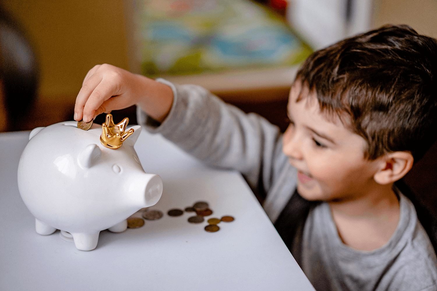 A young child putting money into a piggy bank.