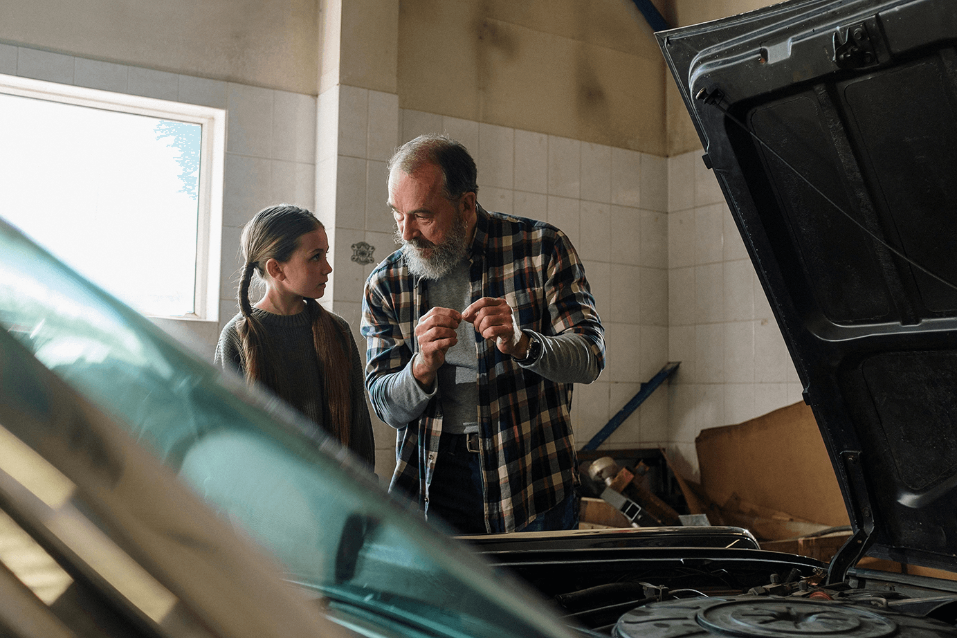 A father figure and young girl working together on a car.