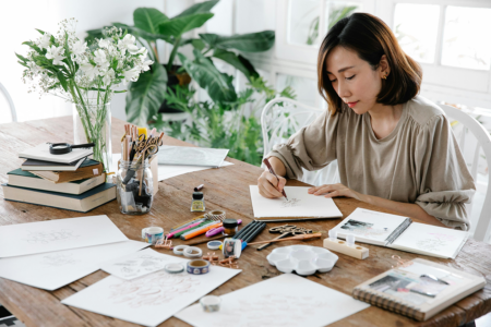 A woman coloring on a piece of sketchbook paper.