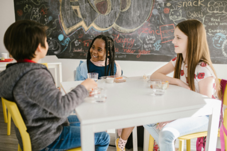 A group of kids talking together at lunch.