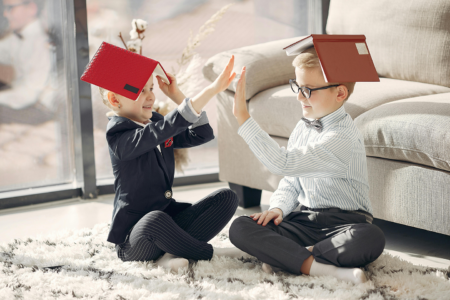 Siblings holding open books on their heads.