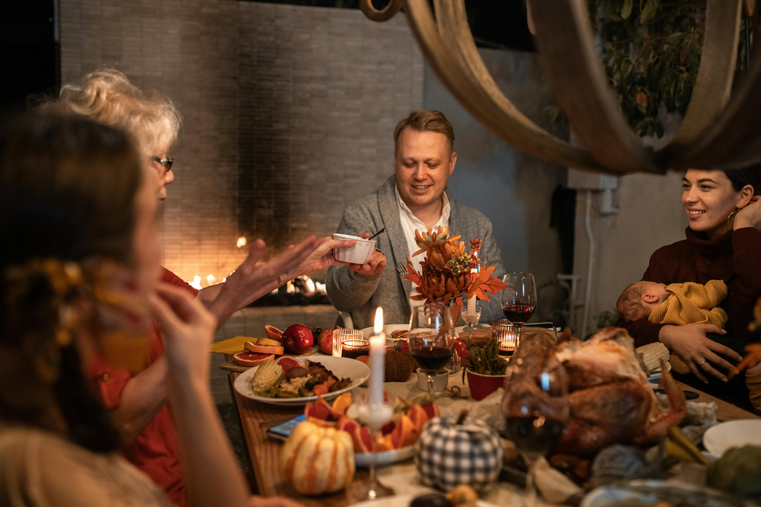 A family passing dishes around the Thanksgiving table while playing a gratitude activity.