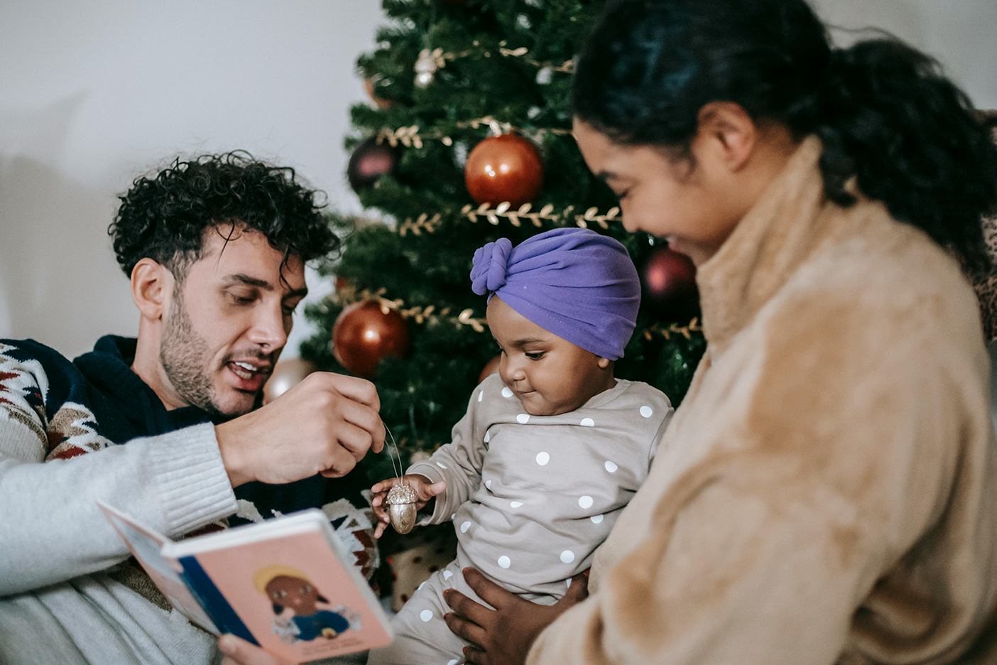 Parents giving their daughter Christmas gifts for Baby.