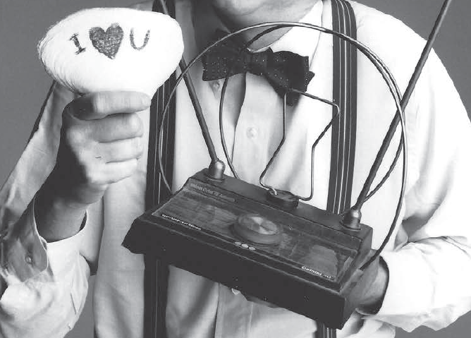 A man holding a painted rock that says “I Heart U” and a vintage set-top TV antenna.