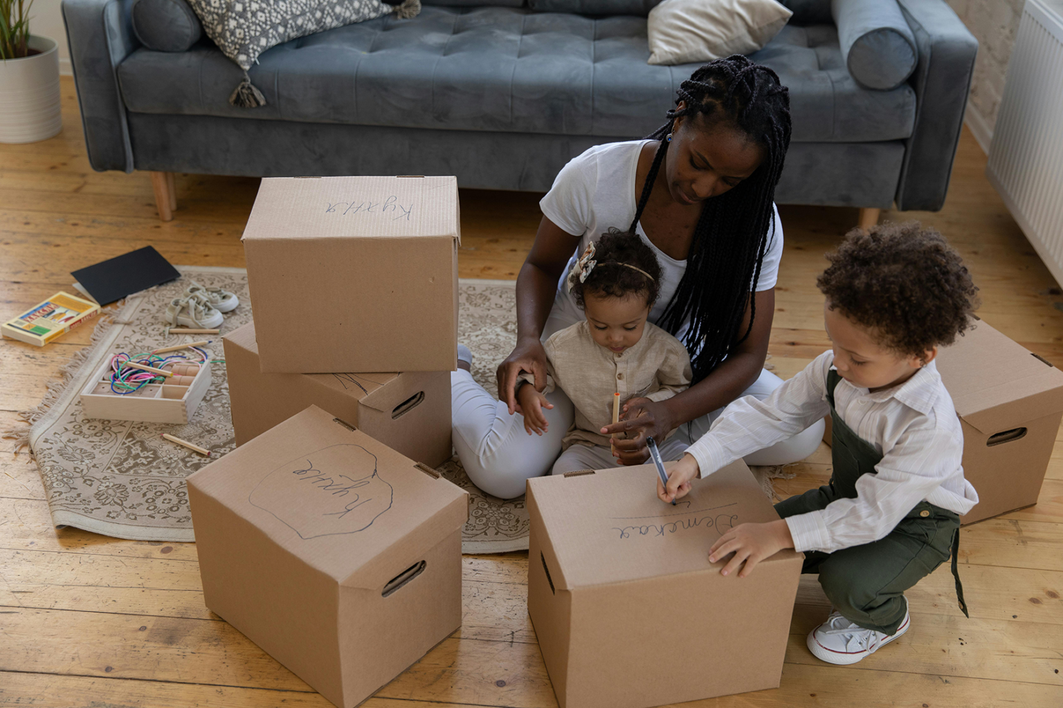 A mom and two kids decluttering and labeling boxes to donate.