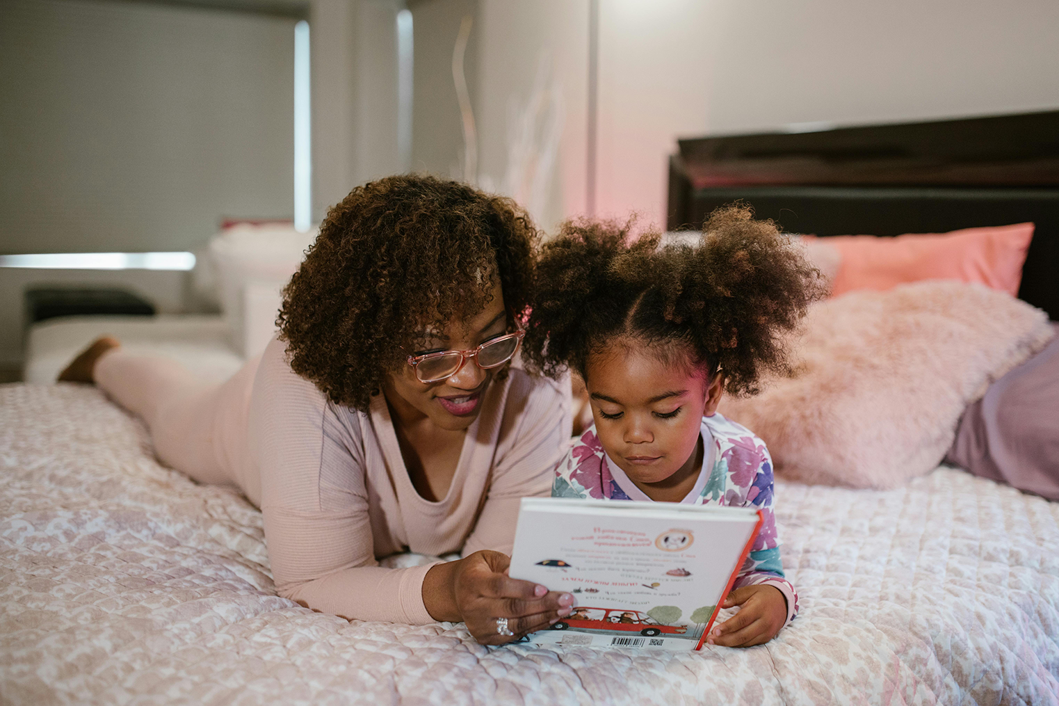 A mom and daughter reading a children’s book together.