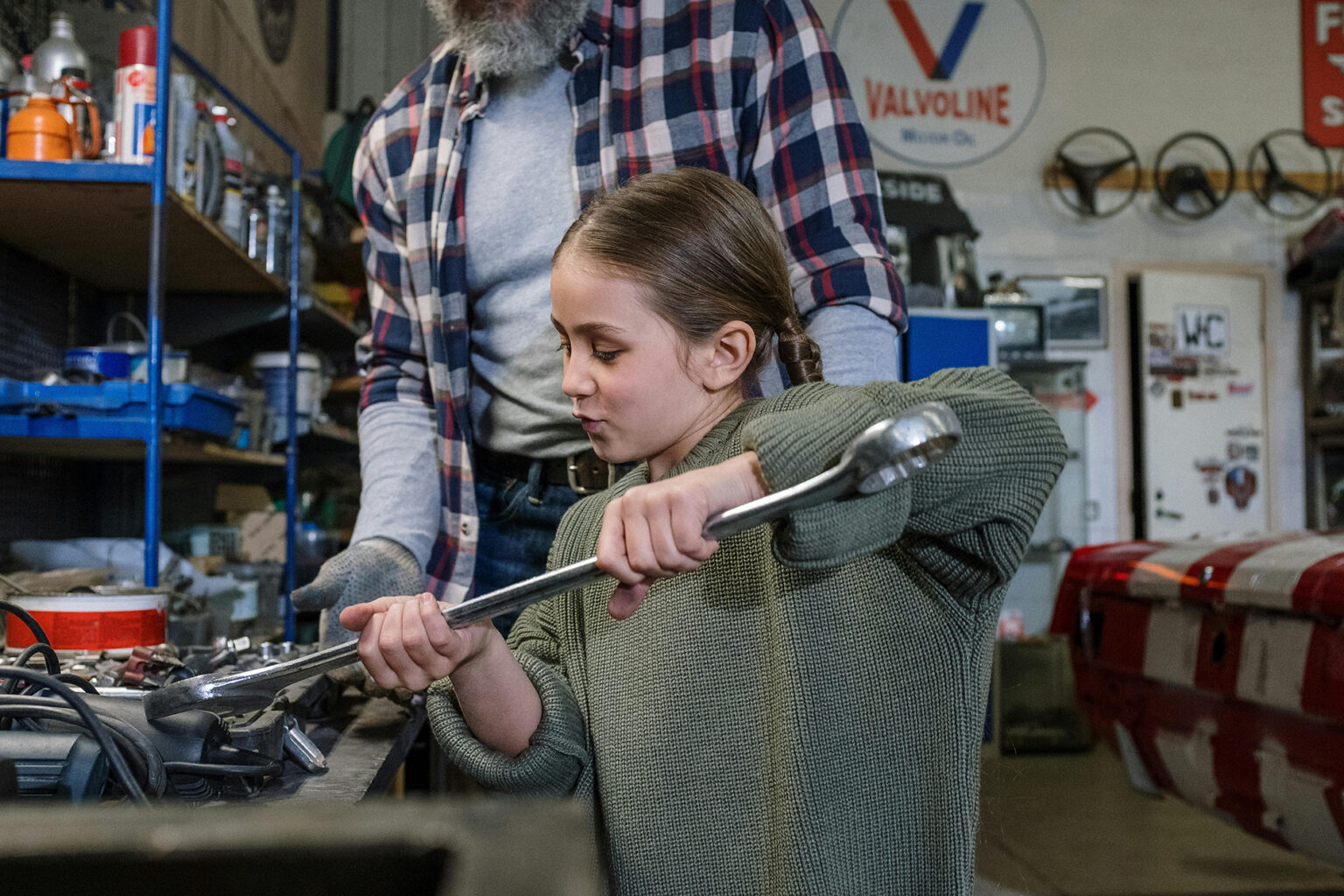 Man and his daughter working together in a garage.