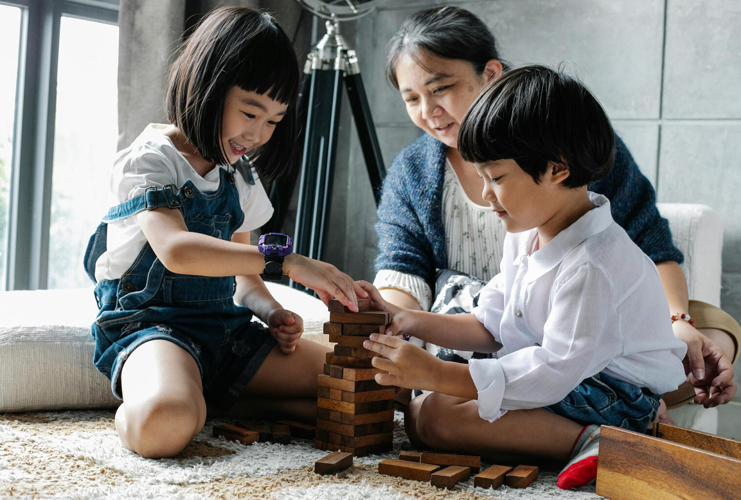 A woman and two children playing a game together on the floor.