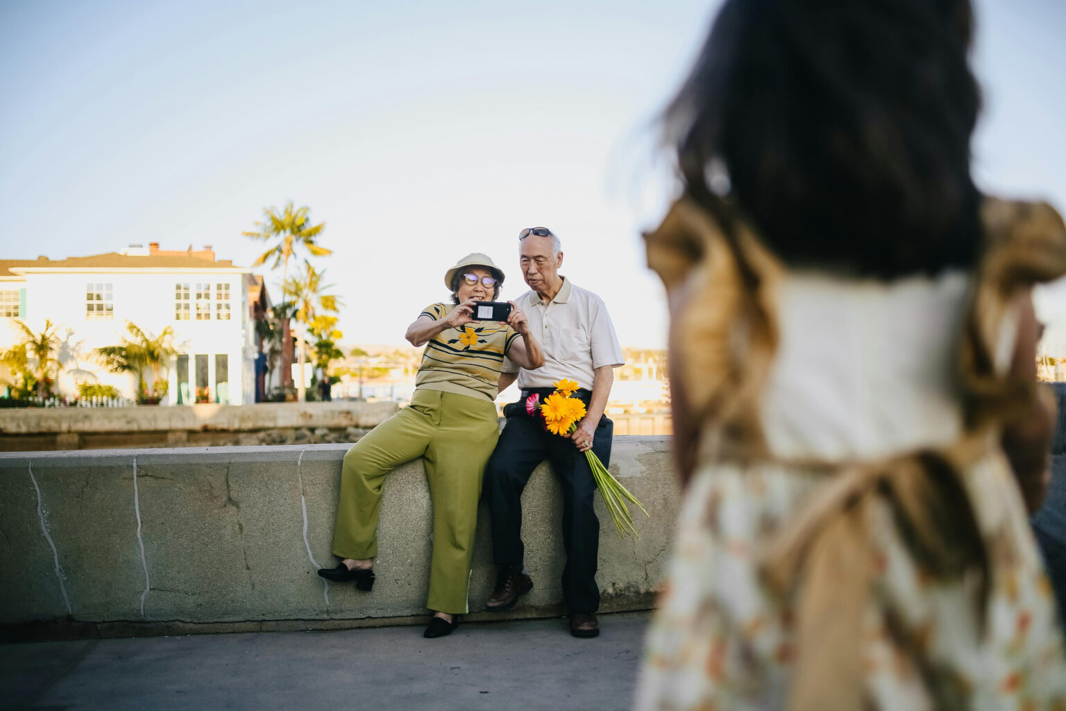 A retired couple taking photos of their granddaughter.