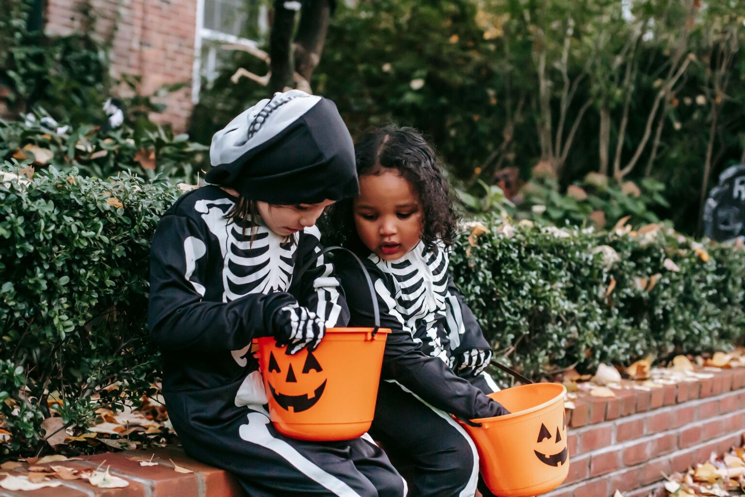 Two girls in Halloween costumes sharing candy.