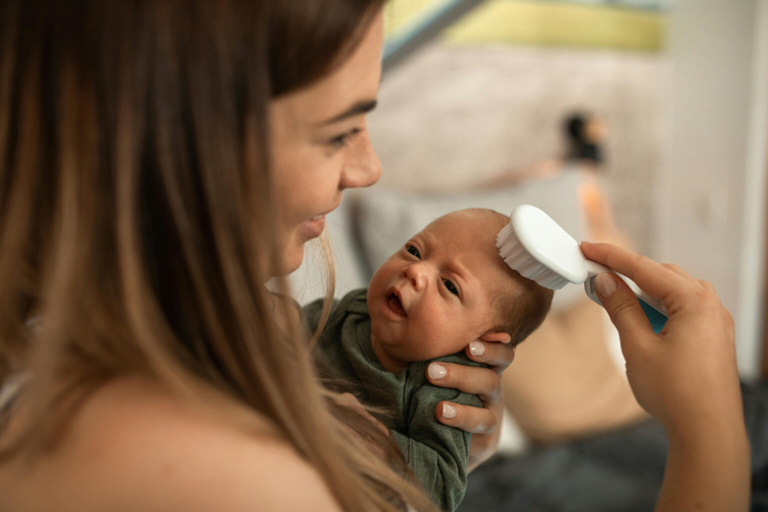 A mom brushing cradle cap patches after applying miracle milk first aid.