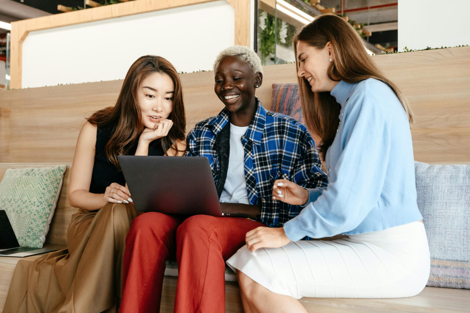Three female coworkers looking at a laptop and talking.