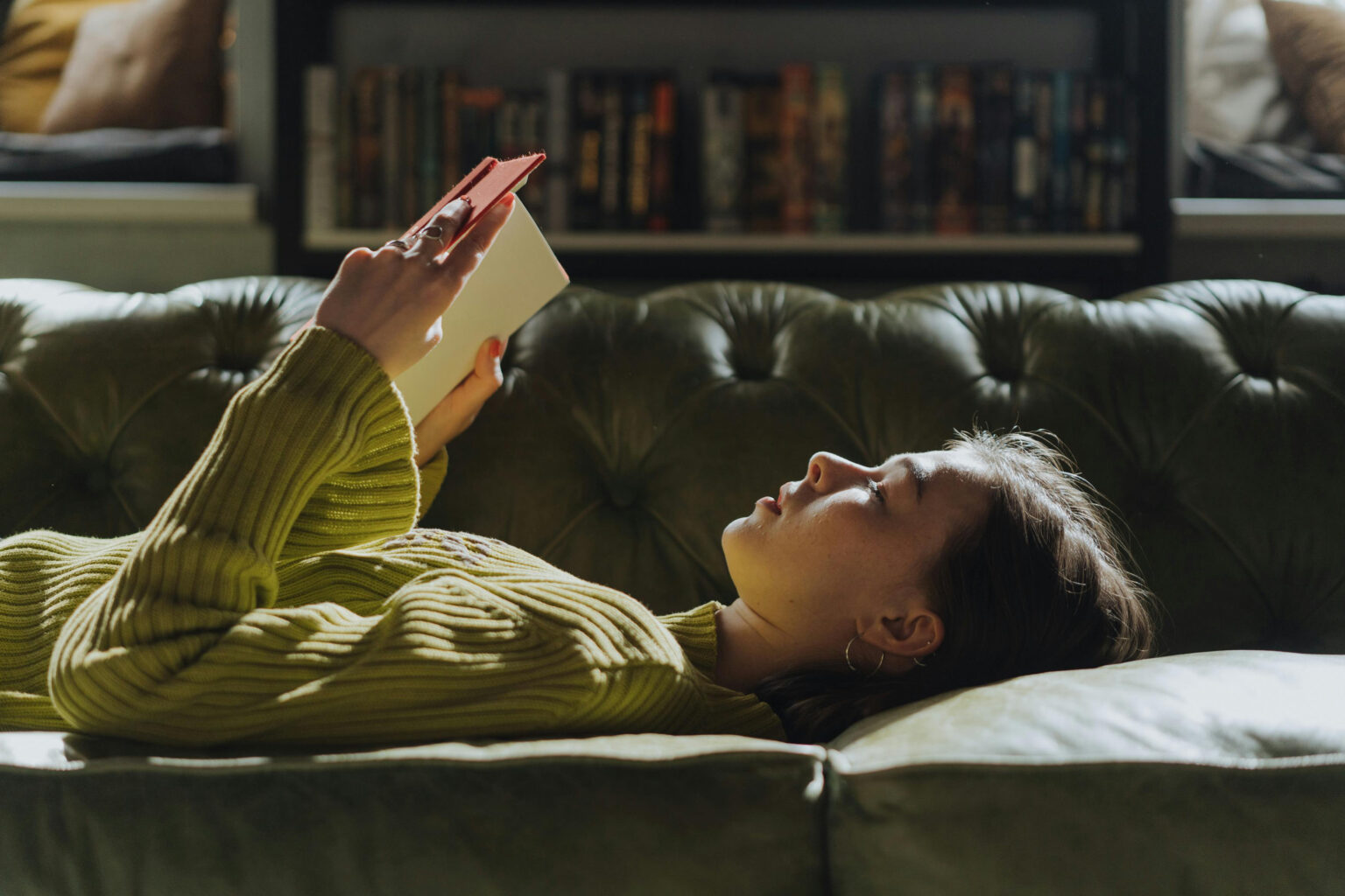 A woman lying on a couch and reading.