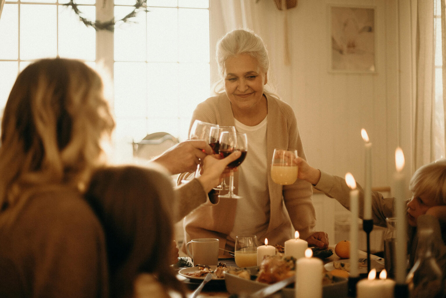 A family sitting at a dinner table and raising their glasses in a toast.