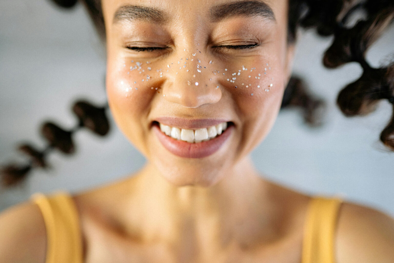 A smiling woman with glitter on her face