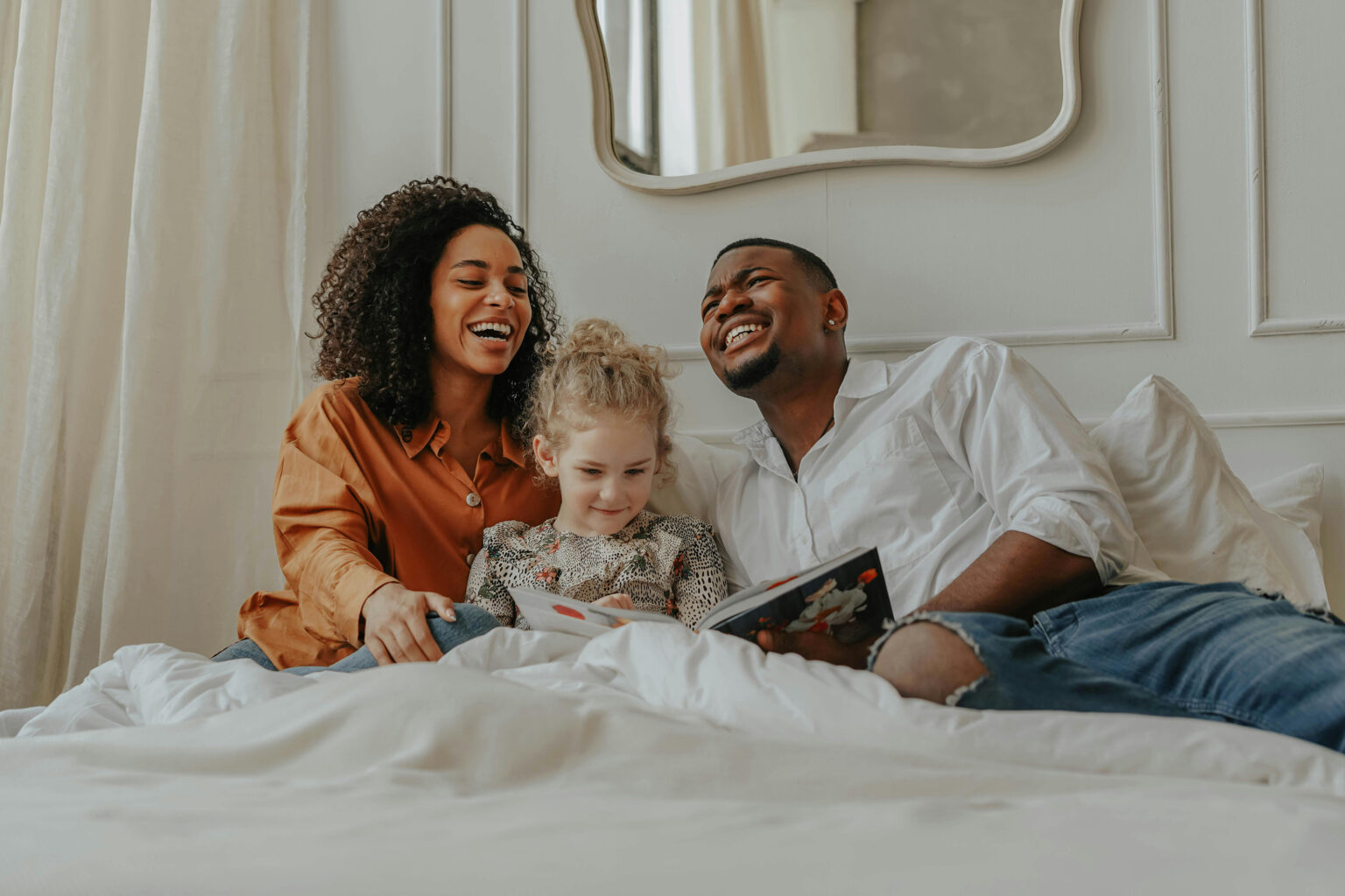 A family of three reading together on a bed