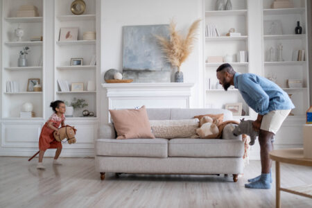 A father and child playing together next to a couch