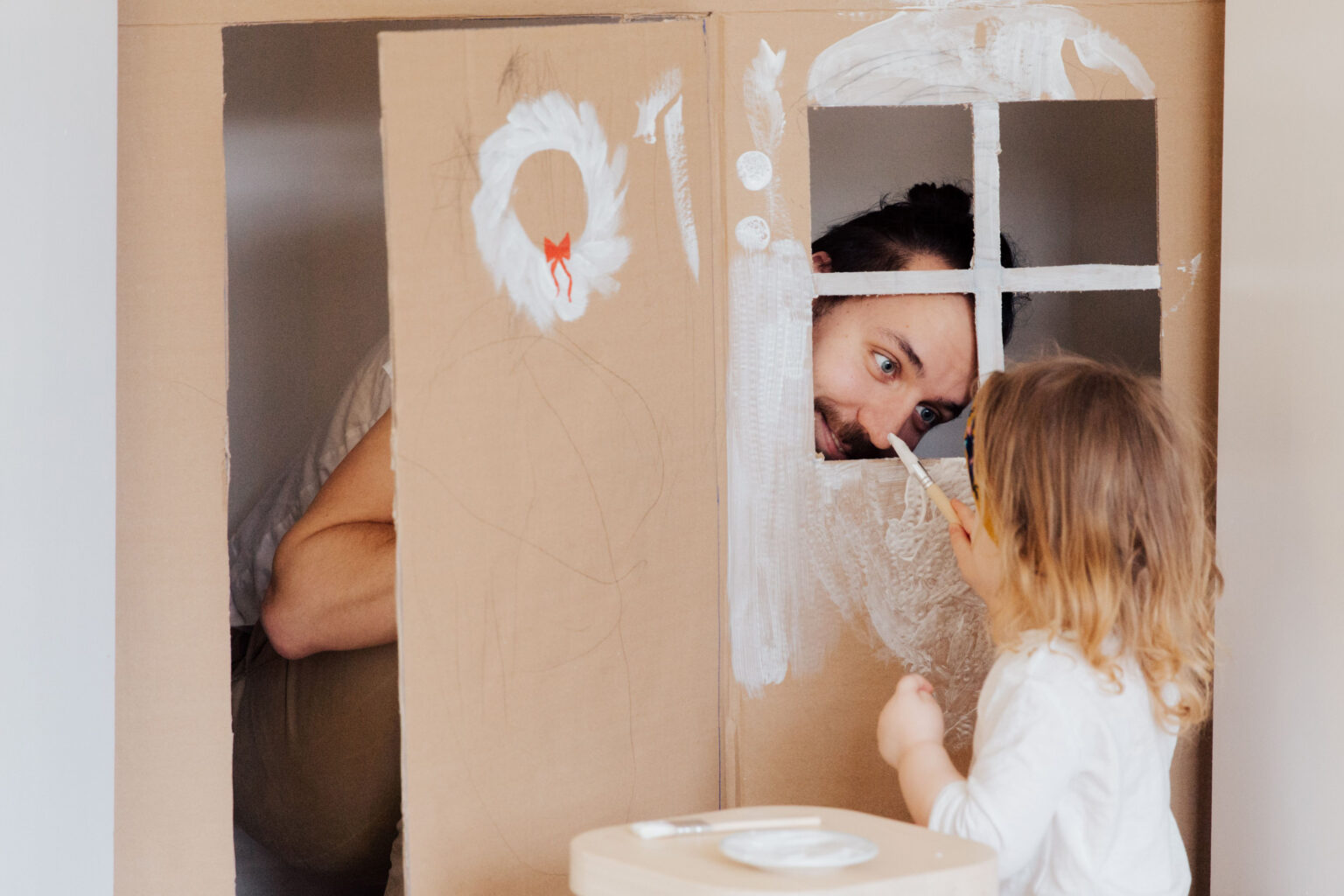 A father and daughter playing in a cardboard house