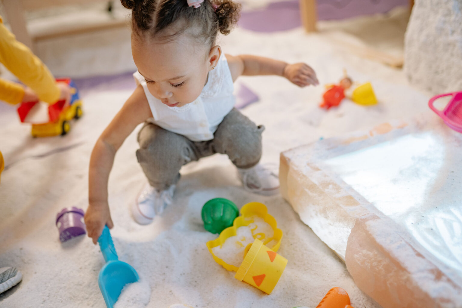 girl playing with toys in a sandbox