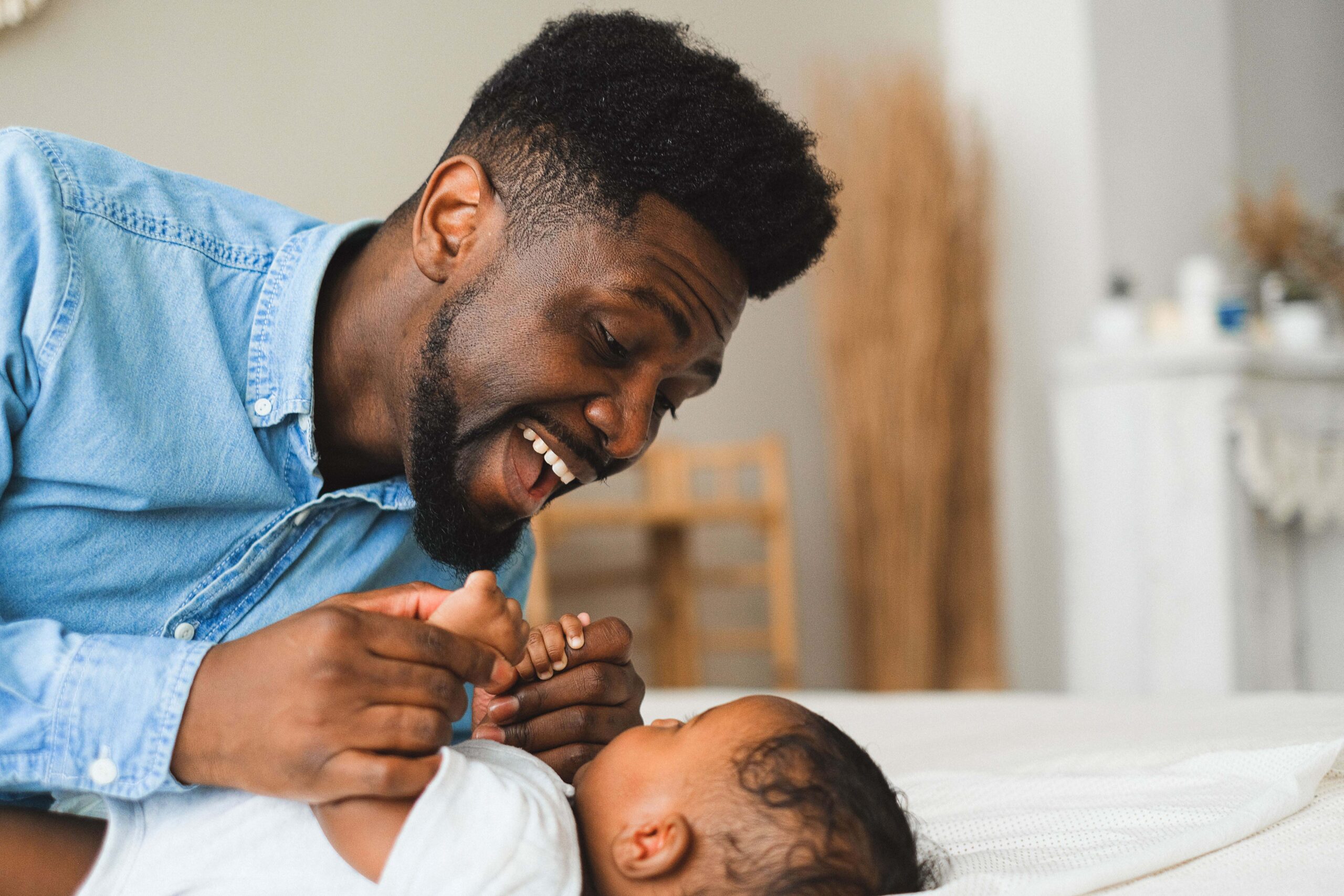 father playing with baby on a bed