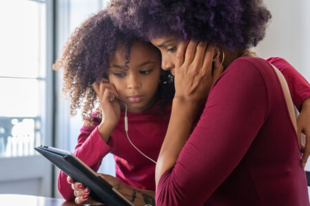 Mother and daughter reading with headphones on
