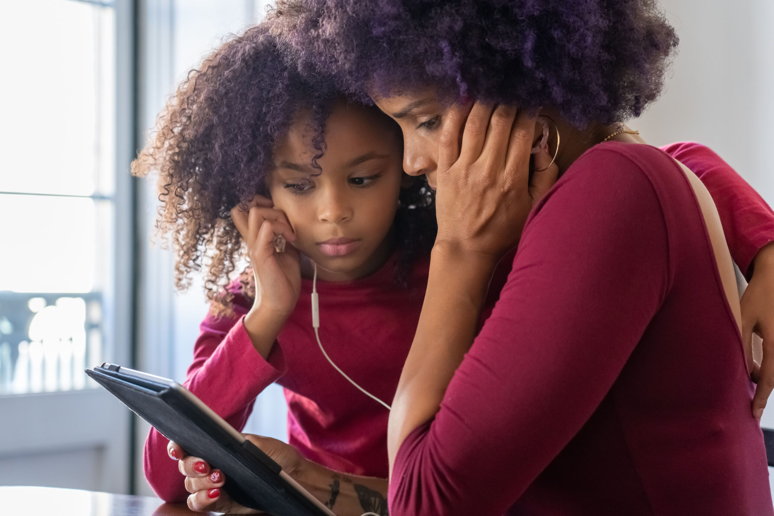 Mother and daughter reading with headphones on