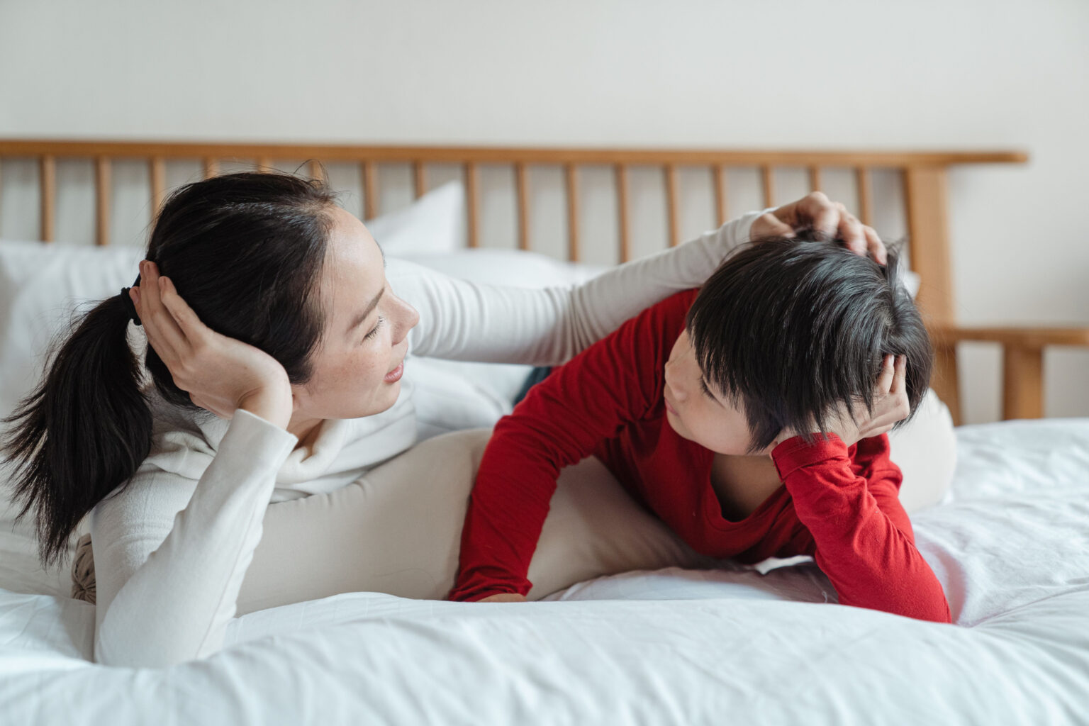 A mom and son lying on a bed talking