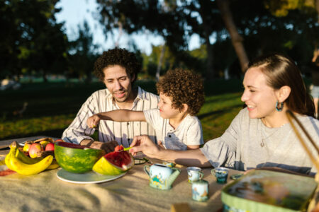 A family eating fruit at a table in a park