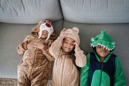 three kids wearing costumes while lying on a couch